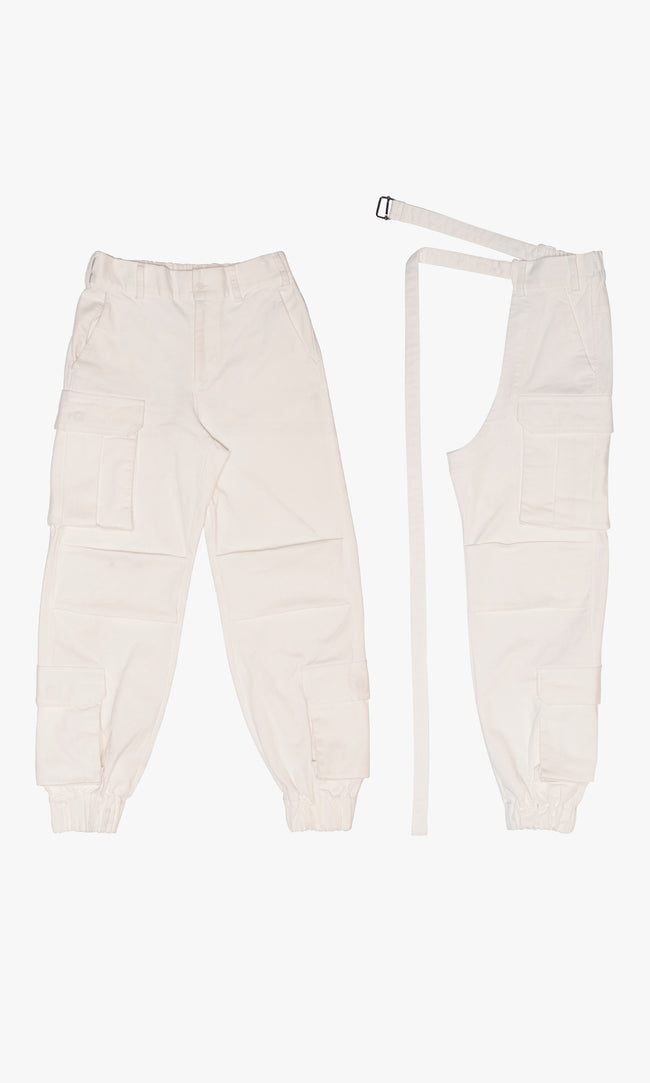 SIEGENTHALER | Back view of the white cotton canvas cargo pants with detachable chaps. Featuring a relaxed elastic waistband, dual back pockets with flaps, and side cargo compartments. The chaps are designed for movement and wrap functionality around the leg.