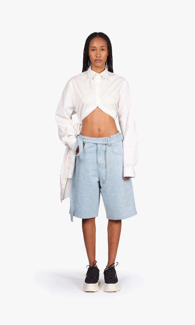 SIEGENTHALER | Front view of the shorts in light blue denim. Cut just above the knee with a wide, structured silhouette. Features contrasted topstitching, five-pocket jean construction, and extended integrated belt straps for versatile styling.