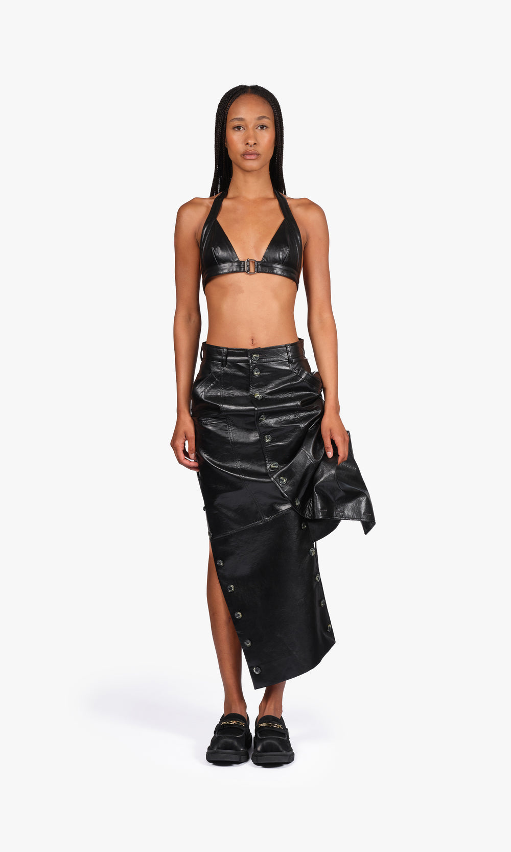 SIEGENTHALER | Full frontal view of the coated black V2 skirt featuring a deconstructed drape, high slit, and asymmetric structure. Articulated through modular buttoning for shape play and layering contrast.