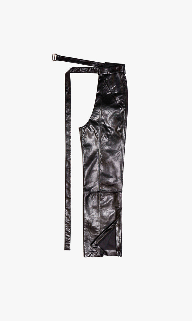  SIEGENTHALER | Modular faux leather chaps featuring a curved open hip construction and extended belt closure. Detailed with articulated paneling and sharp vertical seams, this piece is designed to wrap around trousers or shorts, adding sculptural definition and edge.