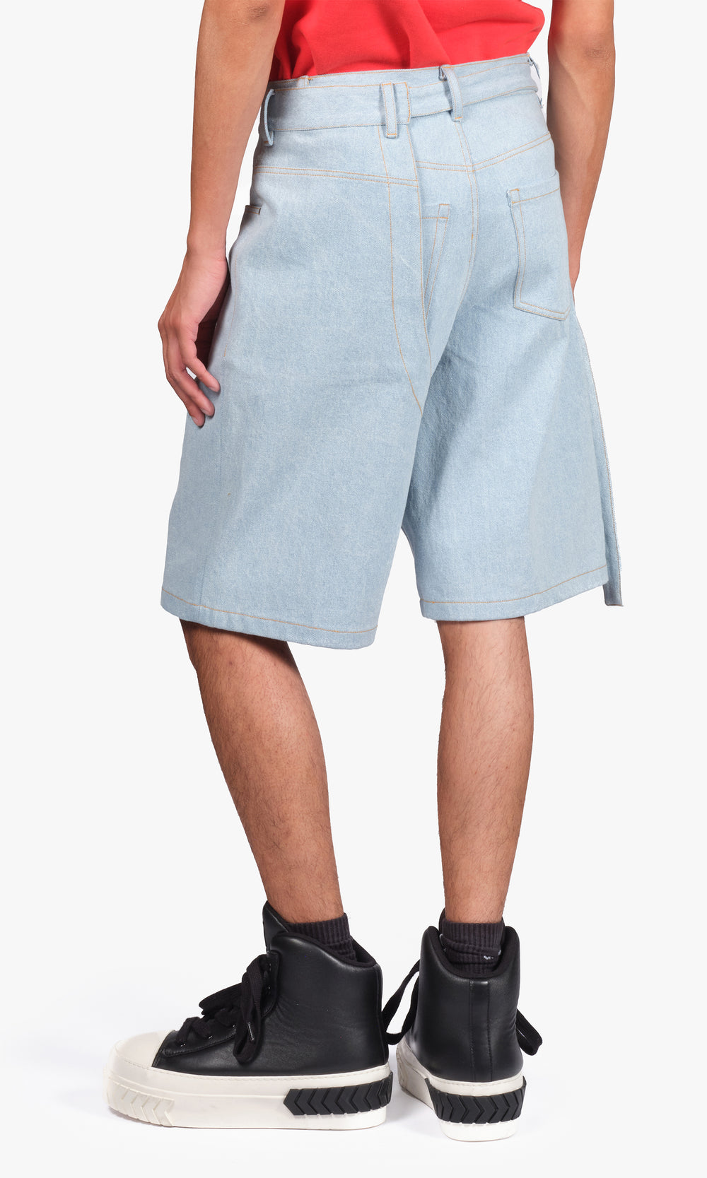 SIEGENTHALER | Rear view of the light denim shorts showcasing the brand’s curved seam signature and raw practicality. Relaxed volume and a deconstructed darted belt loop nod to tailored irreverence.